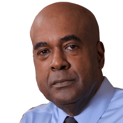 A serious-looking man in a blue shirt and tie. His expression conveys confidence, suggesting a leadership role or expert perspective.